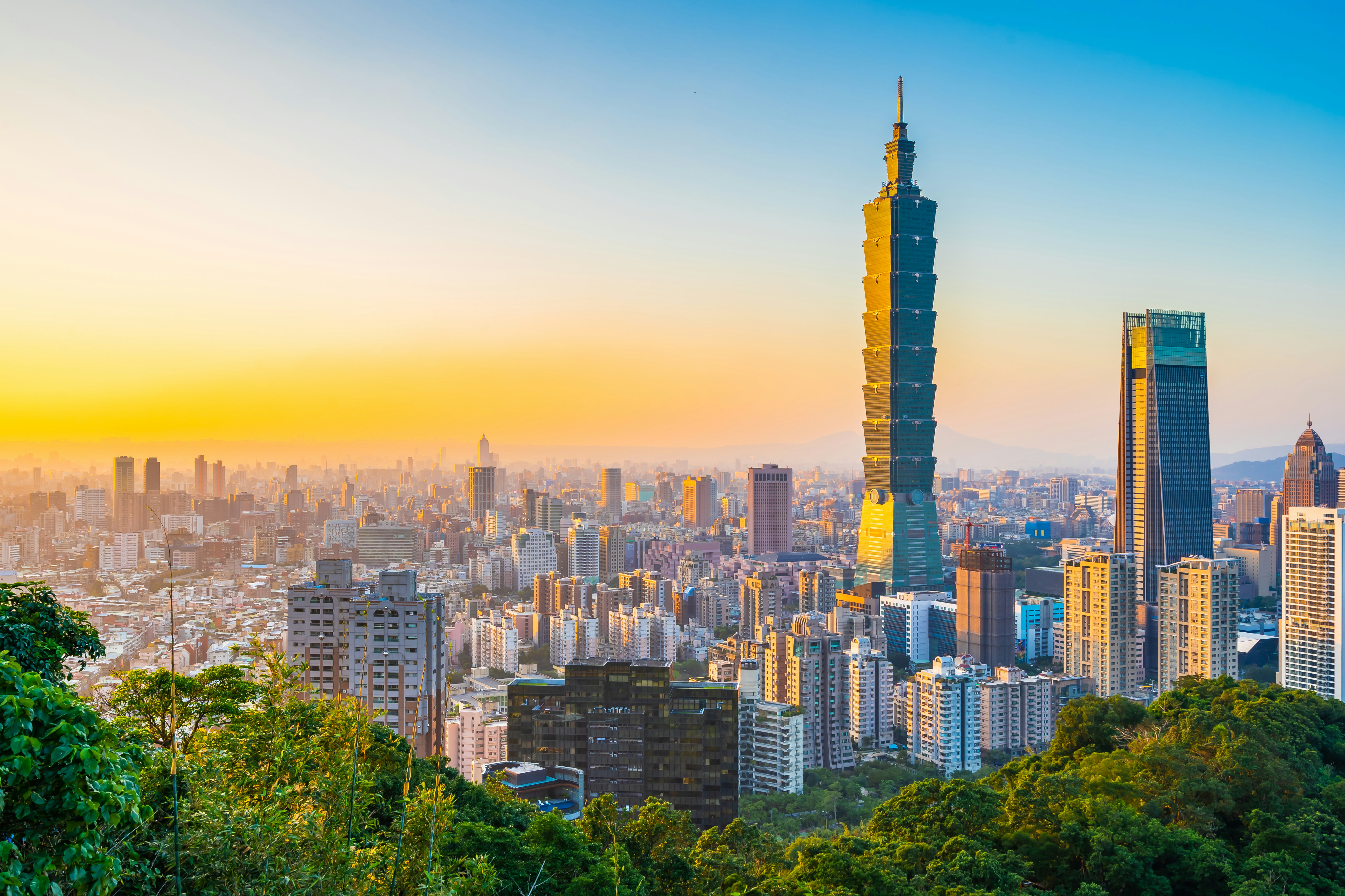 Taipei 101 towering over the Taipei cityscape at sunset.