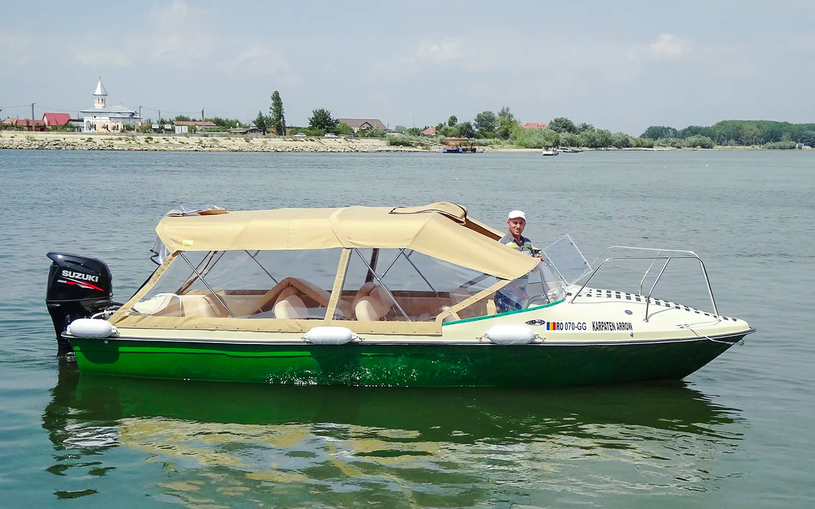 Cruise boat on the Danube Delta with a view of the shoreline and buildings.