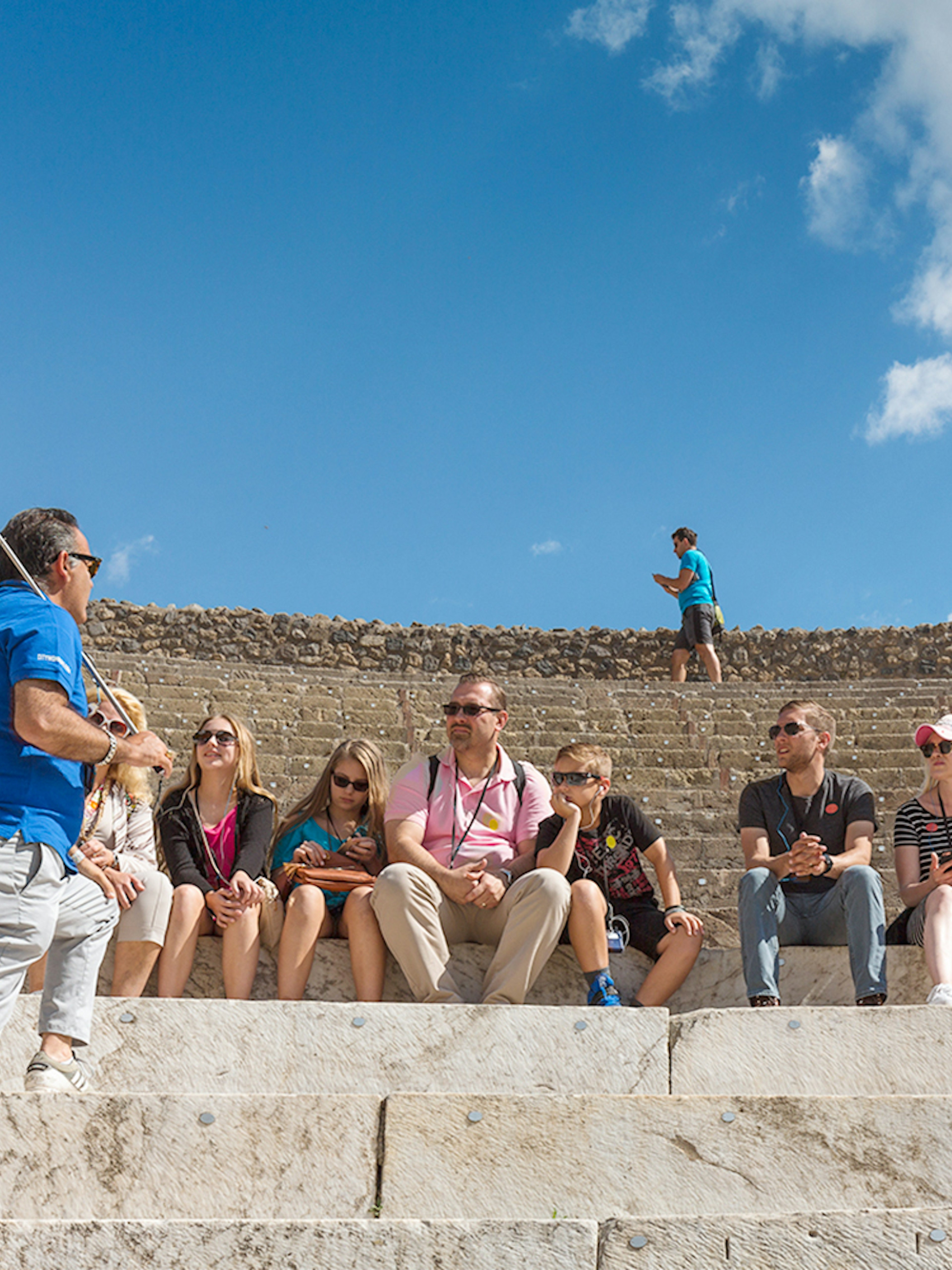 Tour group seated in Pompeii amphitheater with guide, part of Rome day trip.