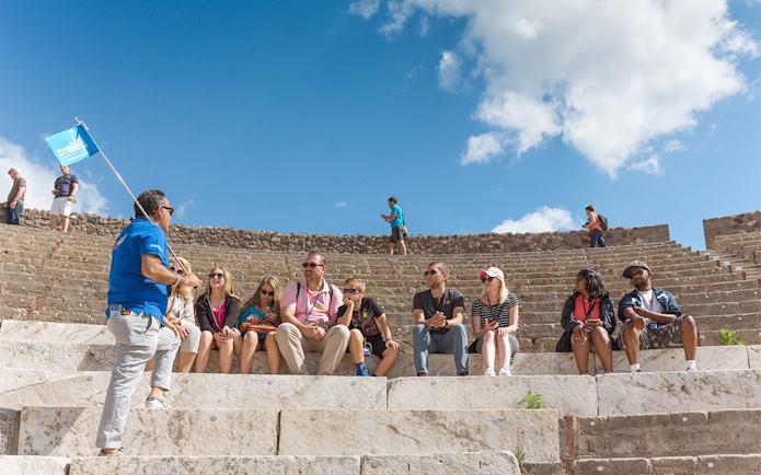 Tour group seated in Pompeii amphitheater with guide, part of Rome day trip.