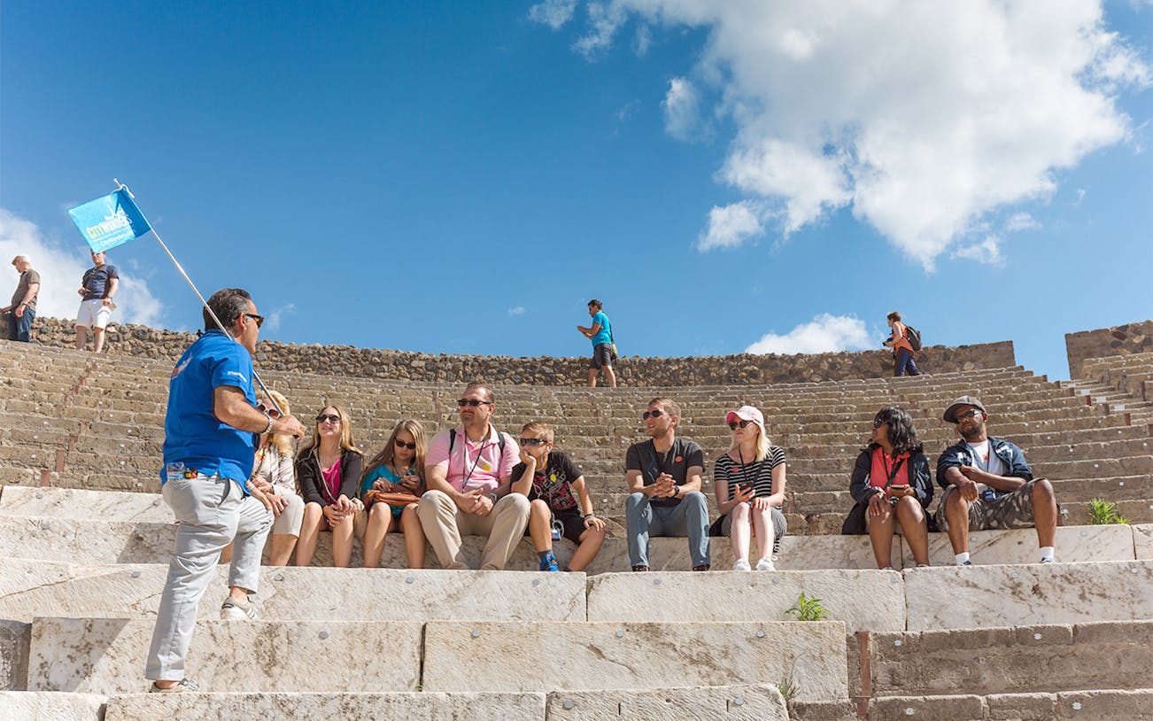Tour group seated in Pompeii amphitheater with guide, part of Rome day trip.