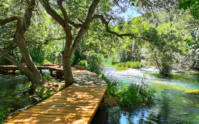 Wooden walkway through lush greenery at Krka National Park, Croatia.