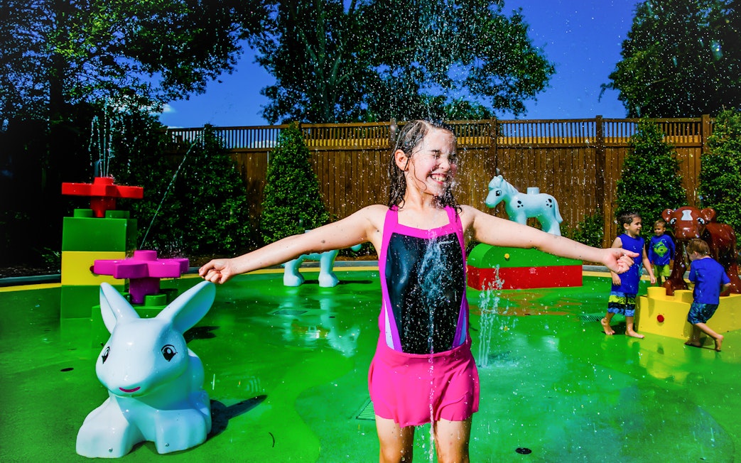 Child playing in Duplo splash area at LEGOLAND Florida with animal figures.