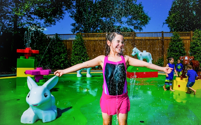 Child playing in Duplo splash area at LEGOLAND Florida with animal figures.