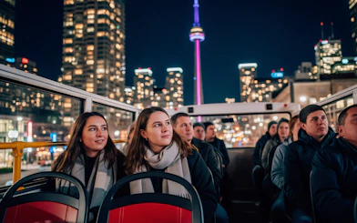Tourists on a night city tour bus with CN Tower in the background, Toronto.