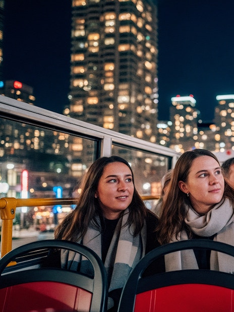 Tourists on a night city tour bus with CN Tower in the background, Toronto.