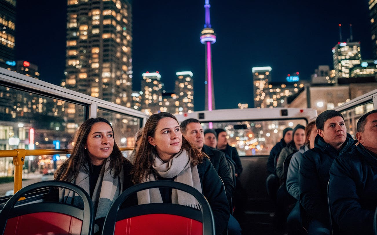 Tourists on a night city tour bus with CN Tower in the background, Toronto.
