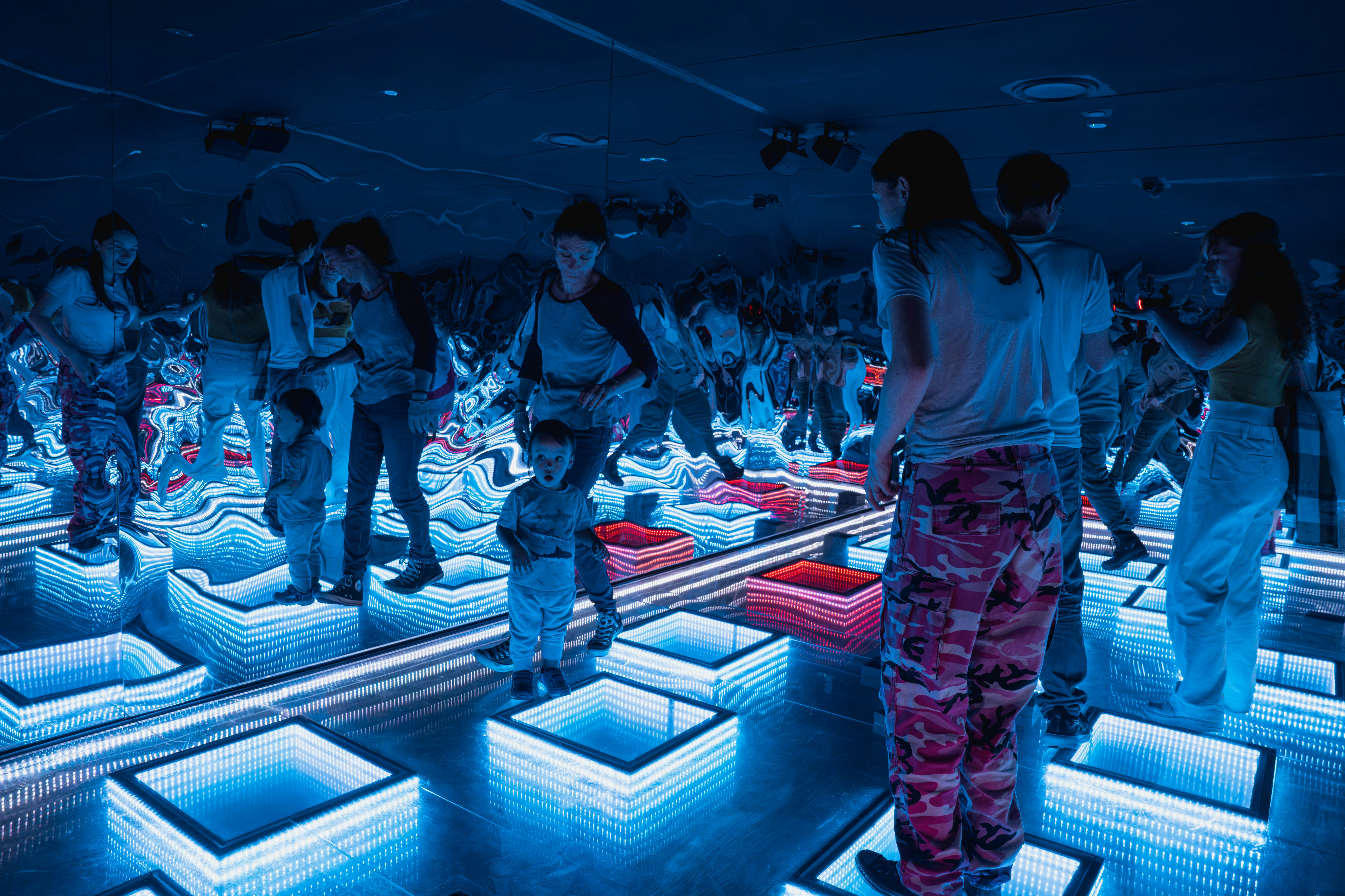 Visitors exploring Chromadance room at Dopamine Land with illuminated floor panels.