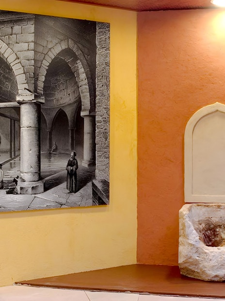 Rudas Thermal Spa interior with historical mural and stone basin.