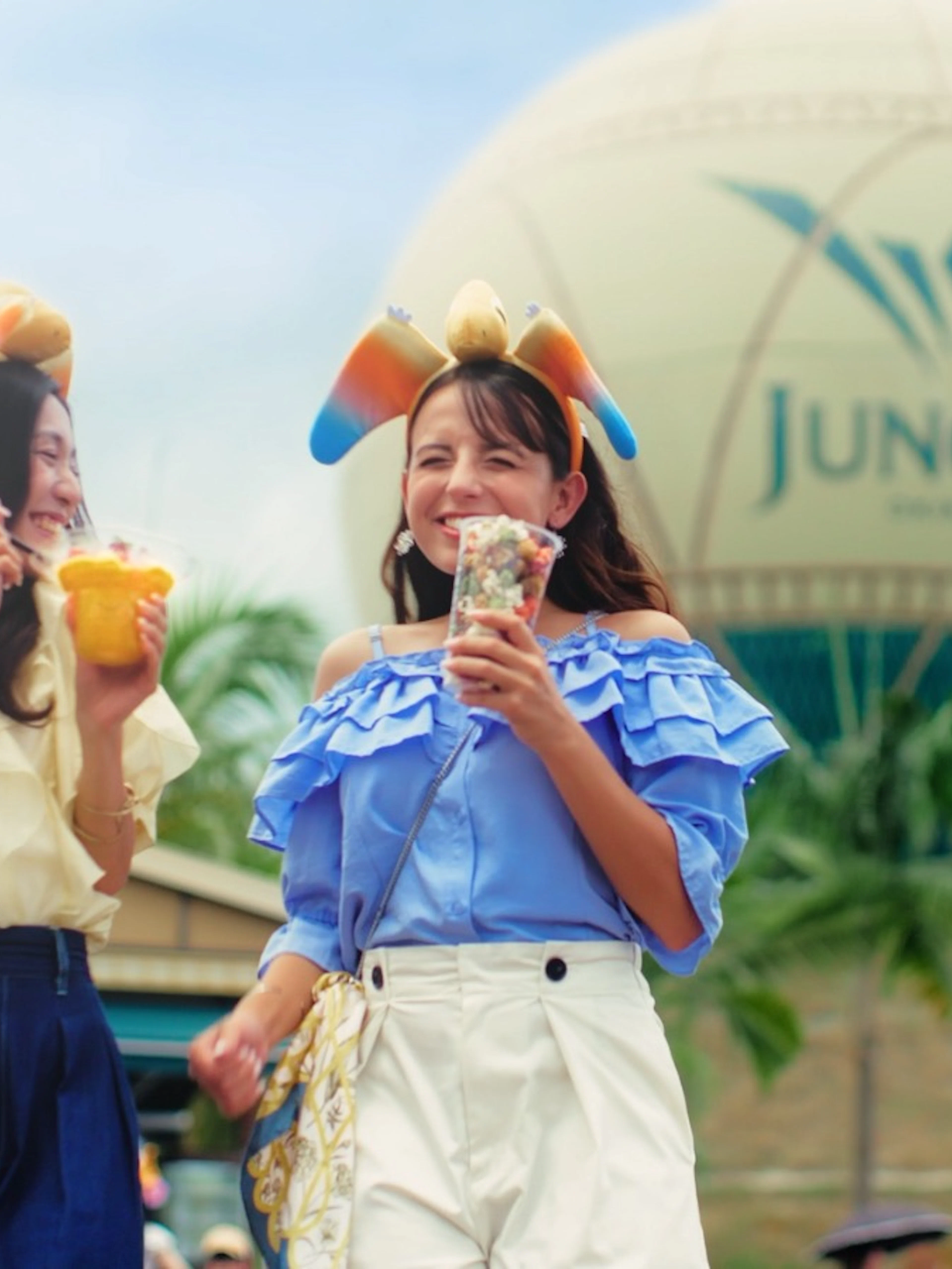 Visitors enjoying snacks at JUNGLIA OKINAWA Park with the park's balloon in the background.