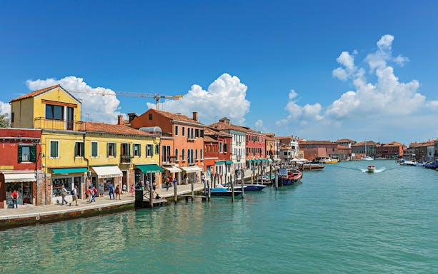 Murano island canal with colorful buildings and boats, Venice public transport tickets.