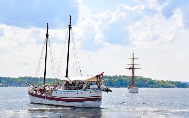 Sailing ship on Oslo fjord sightseeing cruise with distant shoreline.