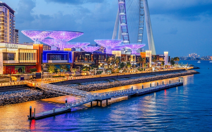 Ain Dubai wheel and illuminated waterfront promenade at dusk.