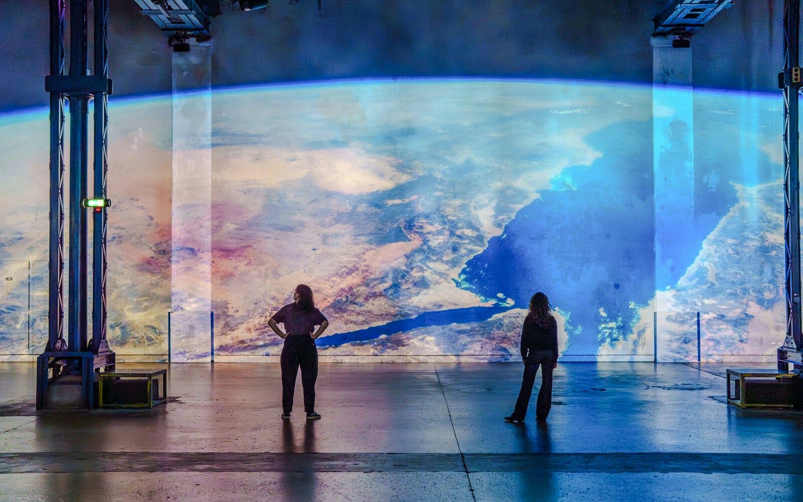 Visitors viewing Earth projection at The Moonwalkers Exhibition, Atelier des Lumières, Paris.