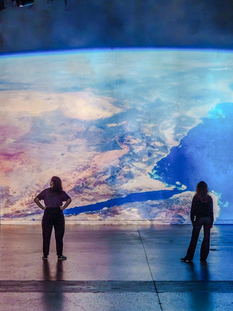 Visitors viewing Earth projection at The Moonwalkers Exhibition, Atelier des Lumières, Paris.