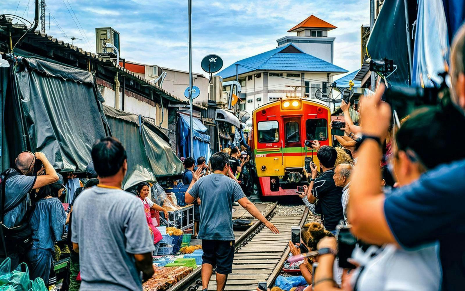 Tourists at Maeklong Train Market in Bangkok as train passes through stalls.