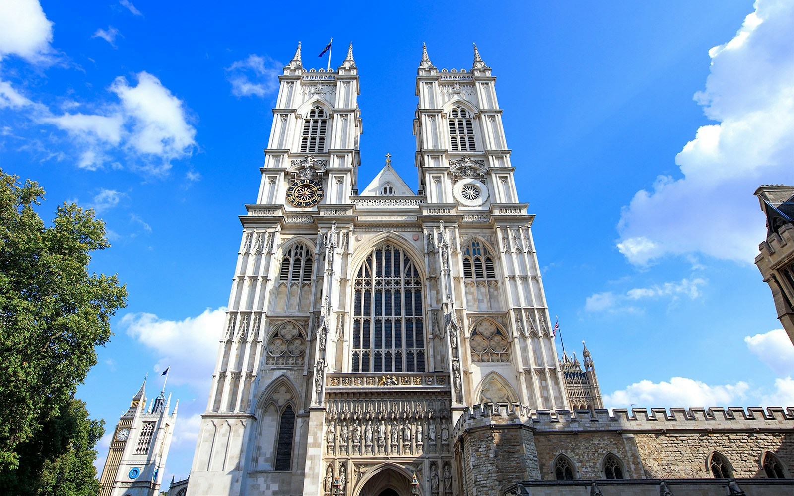 Westminster Abbey facade with bell towers under a clear blue sky.