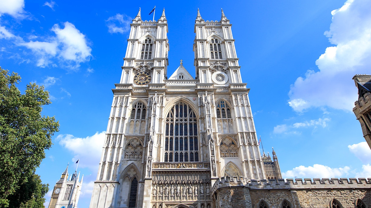 Westminster Abbey facade with bell towers under a clear blue sky.