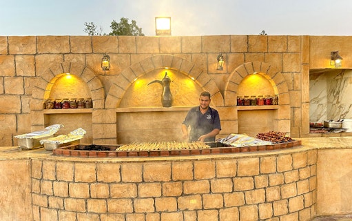 Grill chef preparing skewers at a desert safari barbecue station.