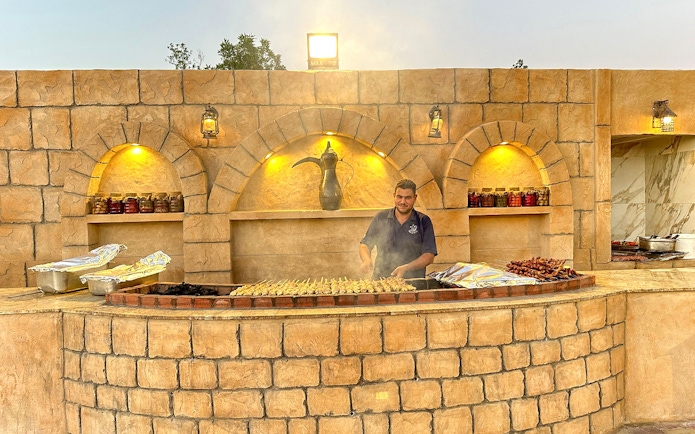 Grill chef preparing skewers at a desert safari barbecue station.