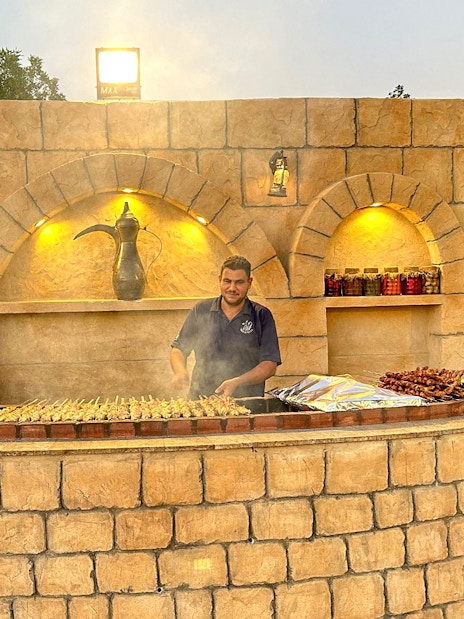 Grill chef preparing skewers at a desert safari barbecue station.