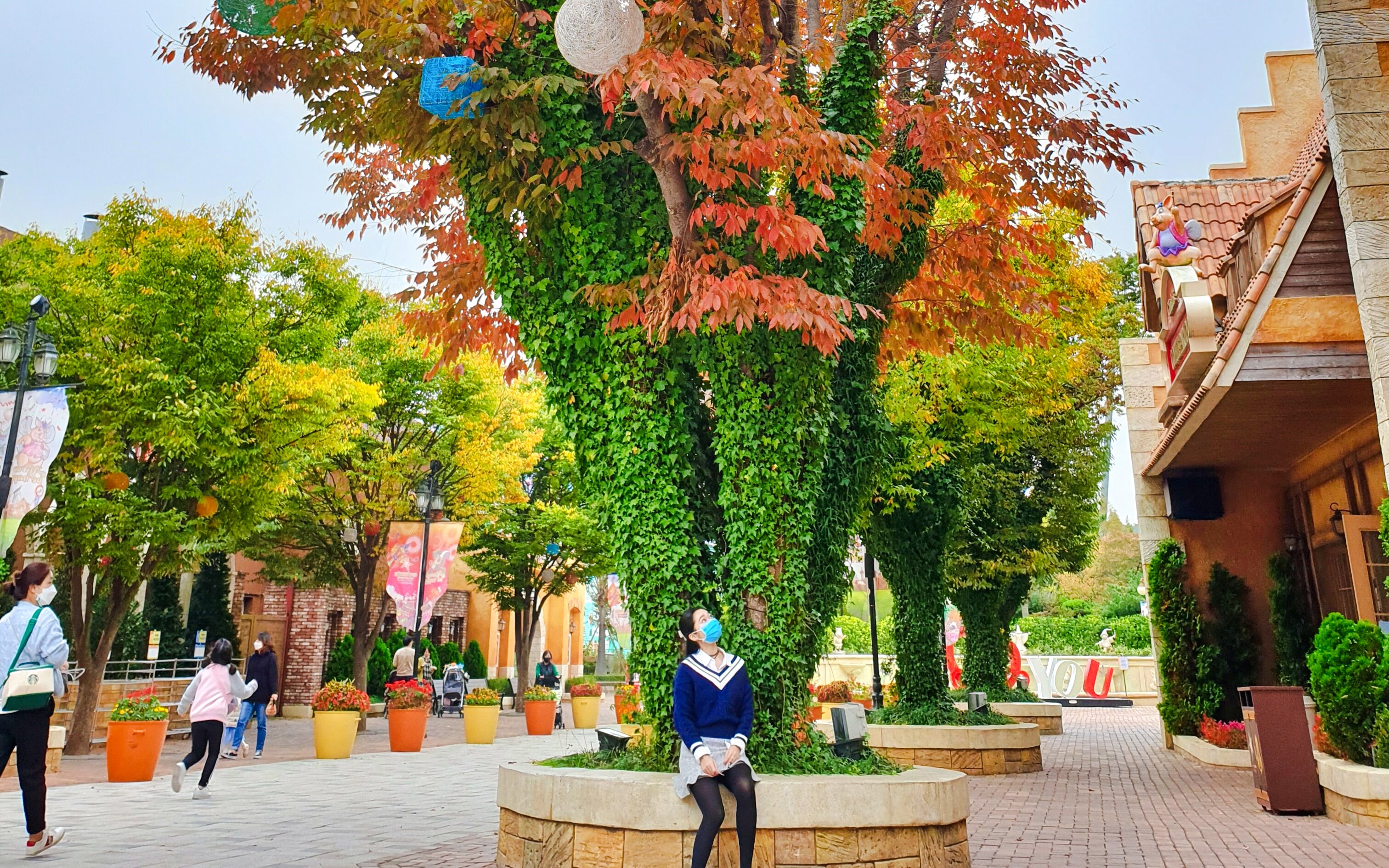 Visitors walking and sitting under colorful autumn trees at Gyeongju World, South Korea.