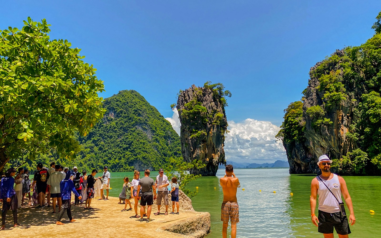 Tourists exploring James Bond Island with limestone cliffs in Phang Nga Bay, Thailand.