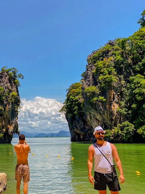 Tourists exploring James Bond Island with limestone cliffs in Phang Nga Bay, Thailand.