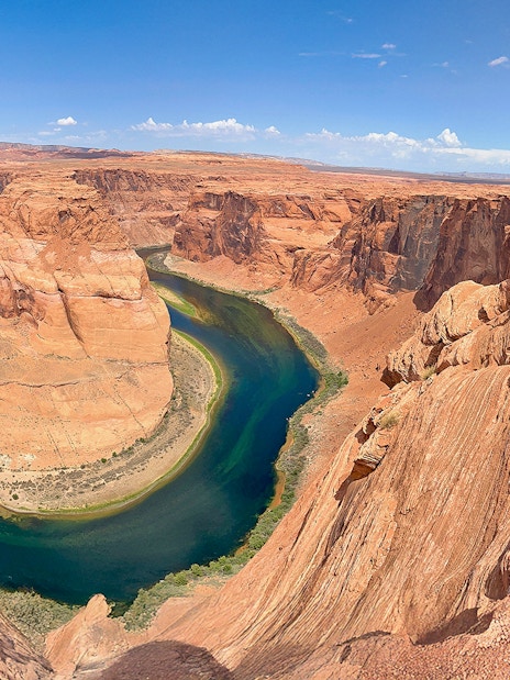 Horseshoe Bend view with a person standing on the edge, part of Lower Antelope Canyon tour from Las Vegas.