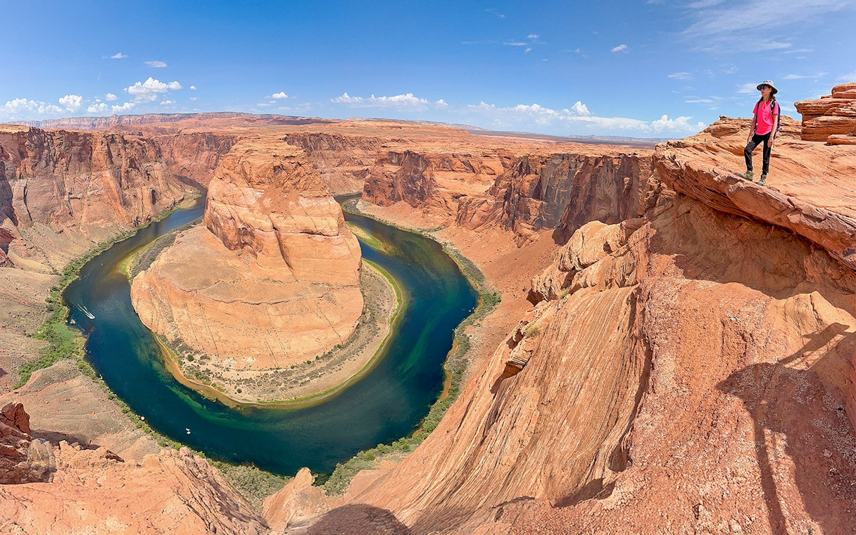 Horseshoe Bend view with a person standing on the edge, part of Lower Antelope Canyon tour from Las Vegas.