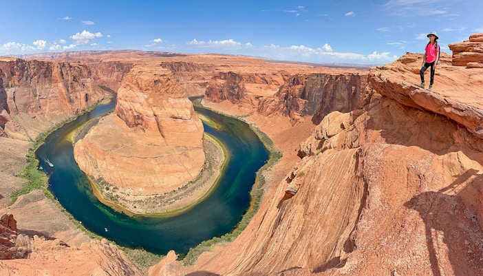 Horseshoe Bend view with a person standing on the edge, part of Lower Antelope Canyon tour from Las Vegas.