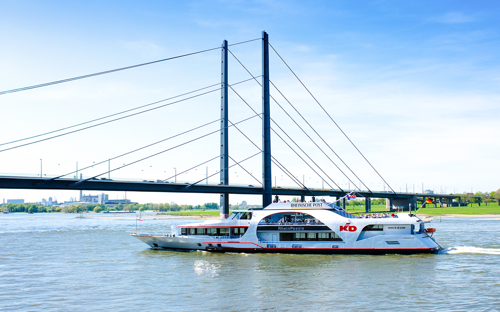 Cruise ship on the Rhine River passing under a bridge in Düsseldorf.