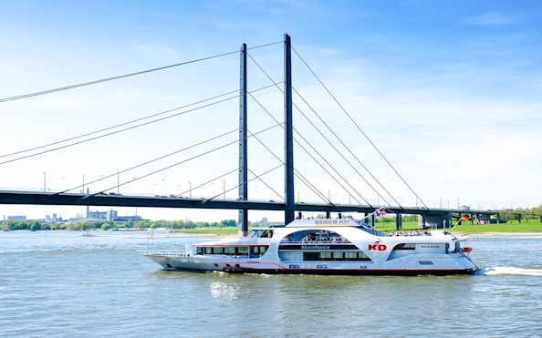 Cruise ship on the Rhine River passing under a bridge in Düsseldorf.