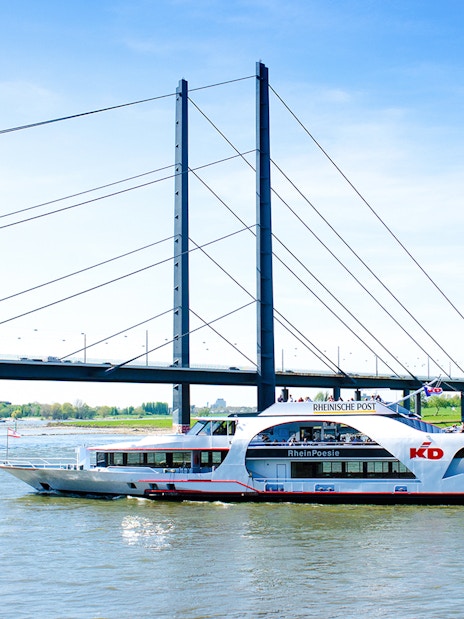 Cruise ship on the Rhine River passing under a bridge in Düsseldorf.