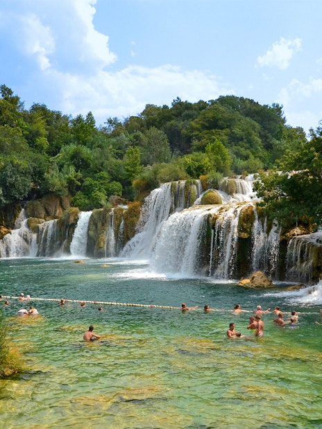 Visitors swimming near waterfalls at Krka National Park, Croatia.