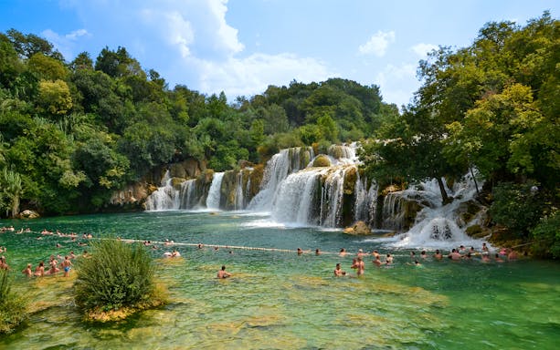 Visitors swimming near waterfalls at Krka National Park, Croatia.