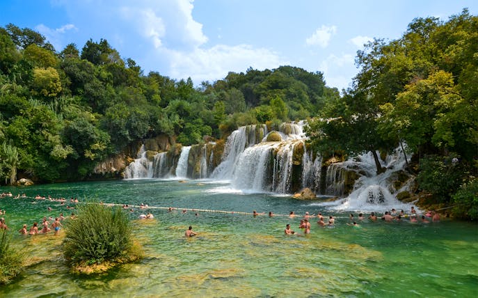 Visitors swimming near waterfalls at Krka National Park, Croatia.