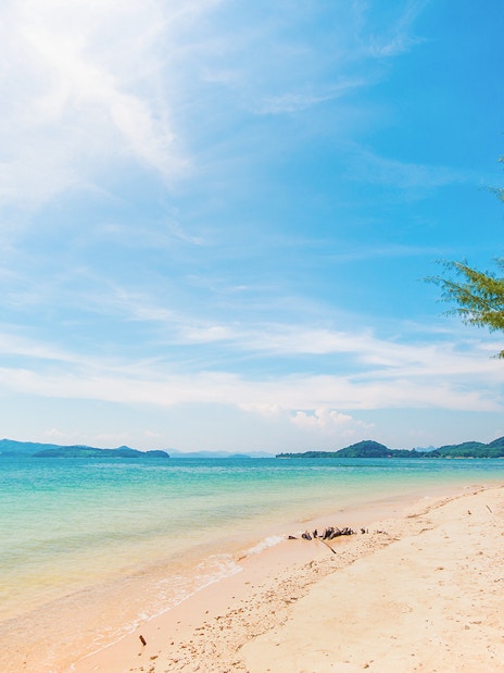 Naka Noi Beach shoreline with clear water and distant hills, ideal for swimming.