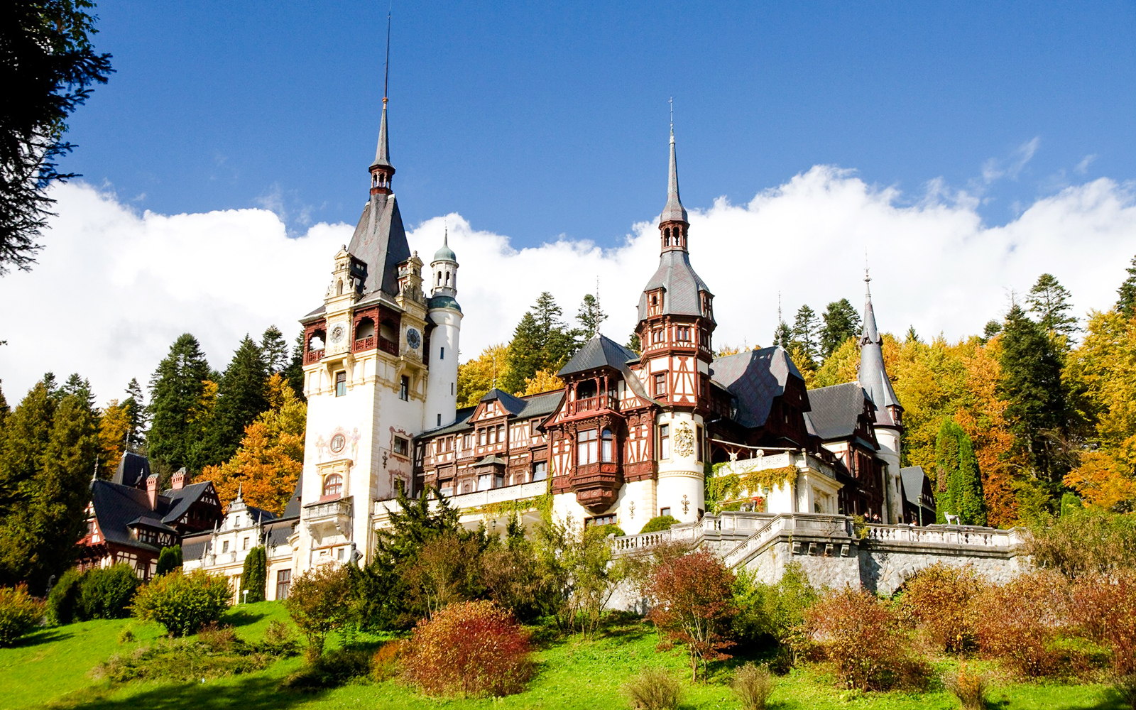 Peleș Castle in Romania surrounded by autumn trees.