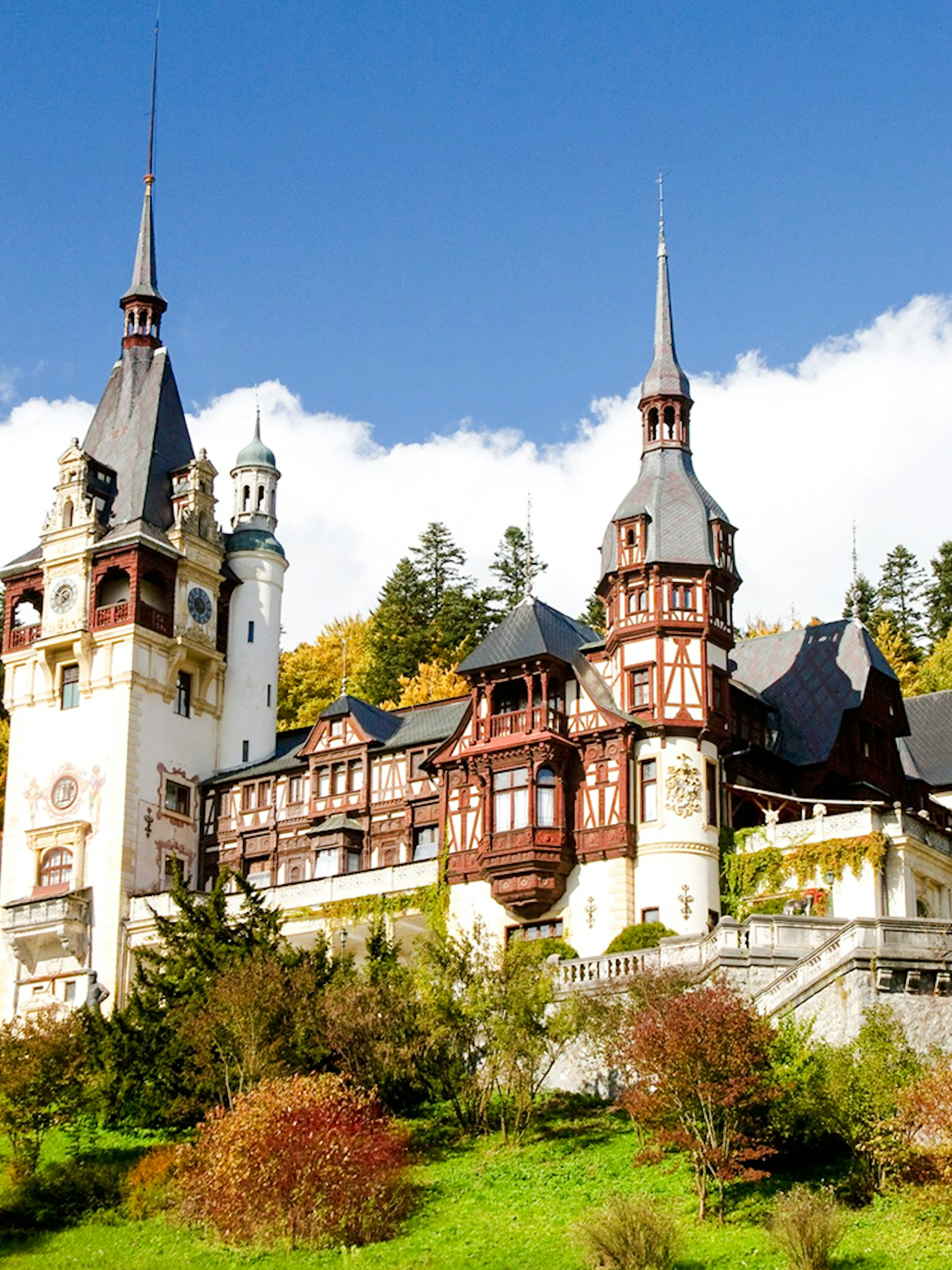 Peleș Castle in Romania surrounded by autumn trees.