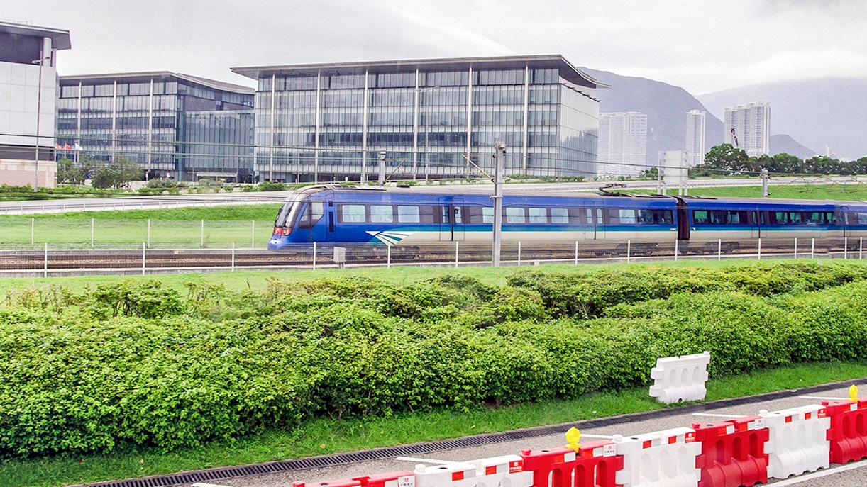 Hong Kong Airport Express train passing modern buildings.