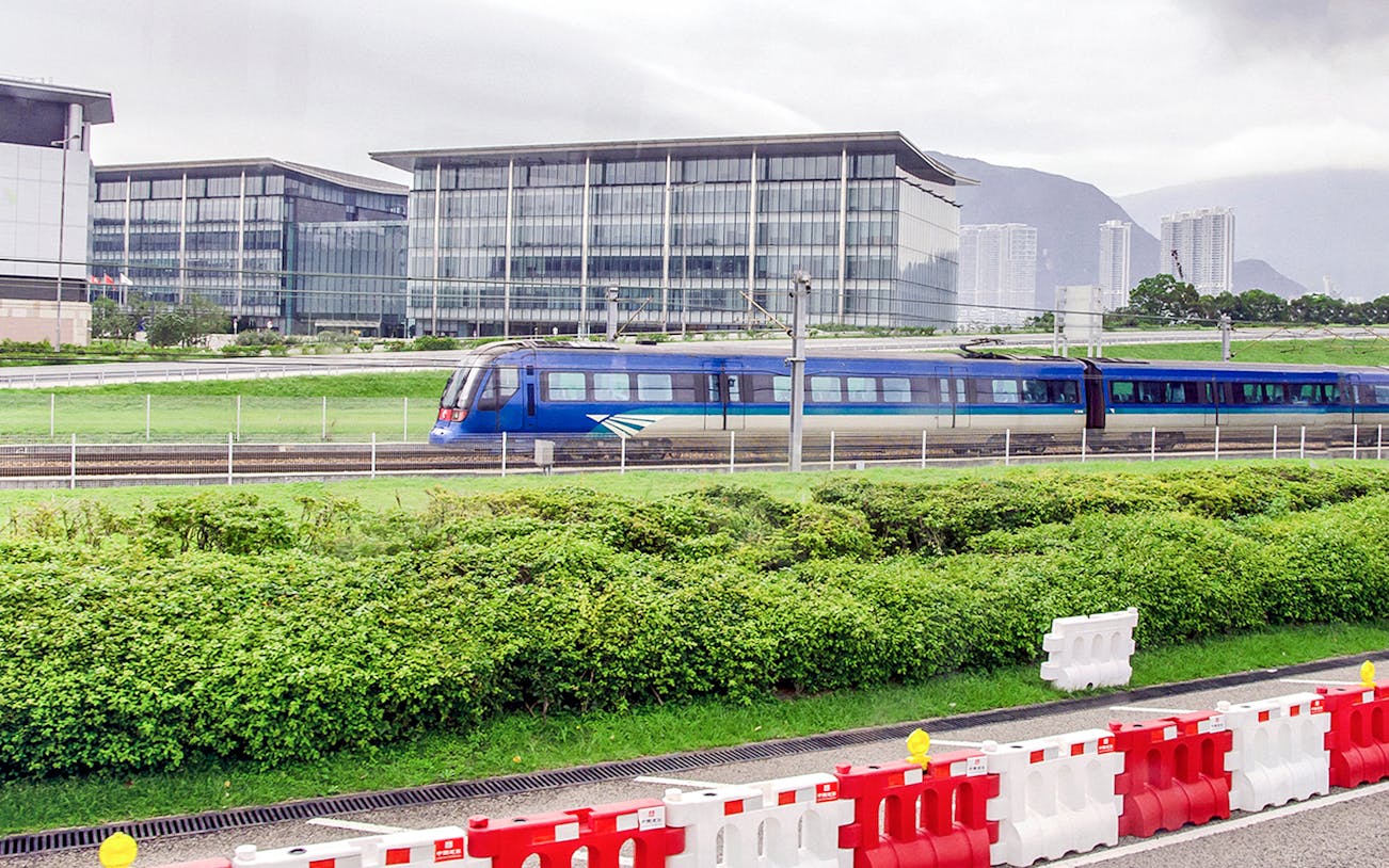 Hong Kong Airport Express train passing modern buildings.
