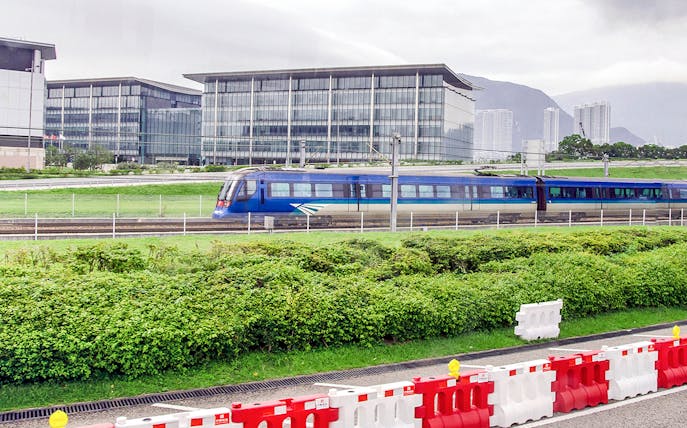 Hong Kong Airport Express train passing modern buildings.
