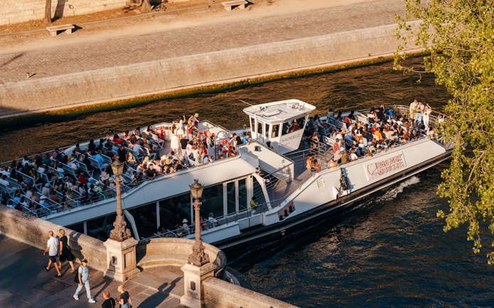 Seine River cruise boat with tourists enjoying an evening ride in Paris.