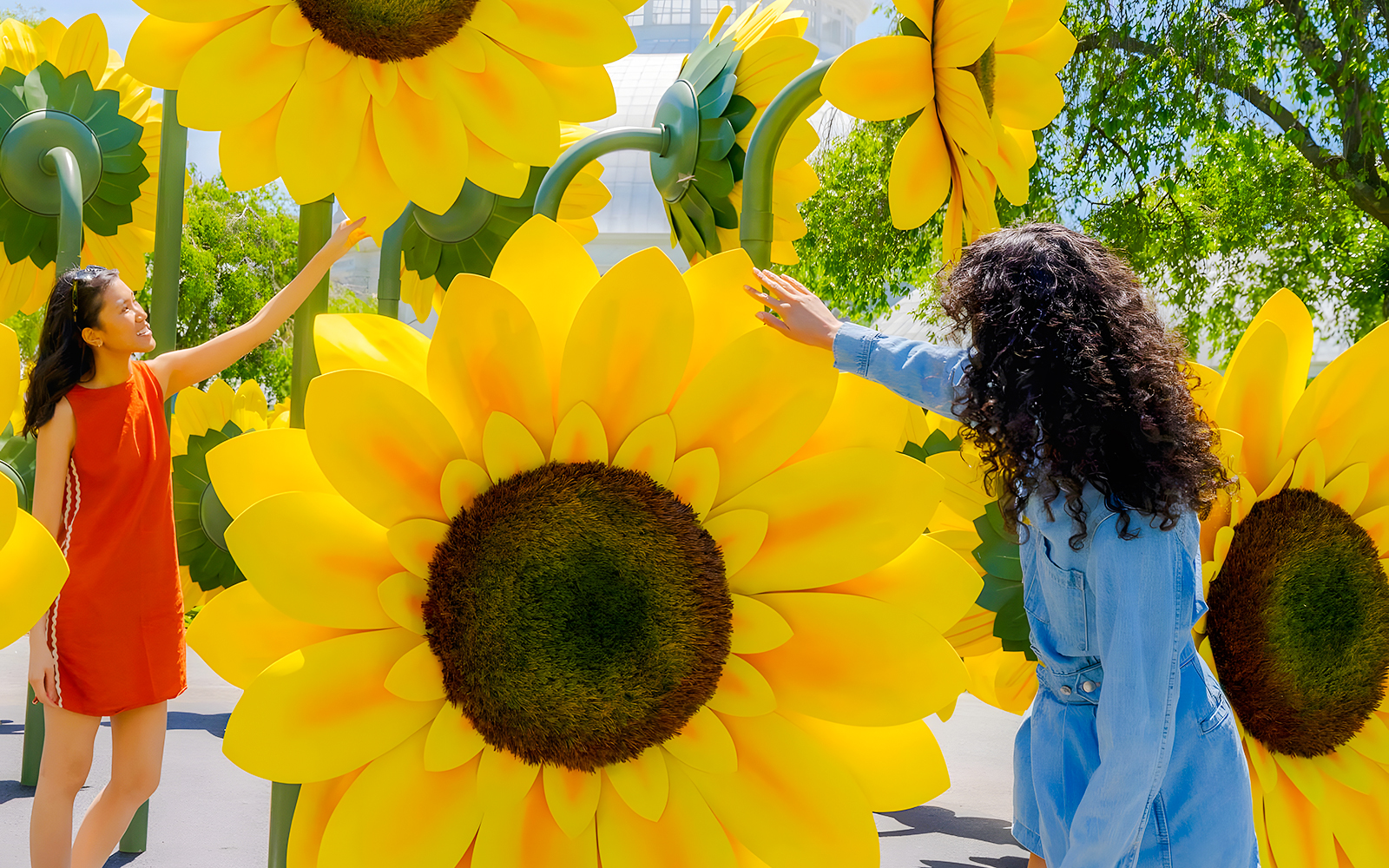 Visitors interacting with large sunflower sculptures at Van Gogh’s Flowers exhibit, NYBG.