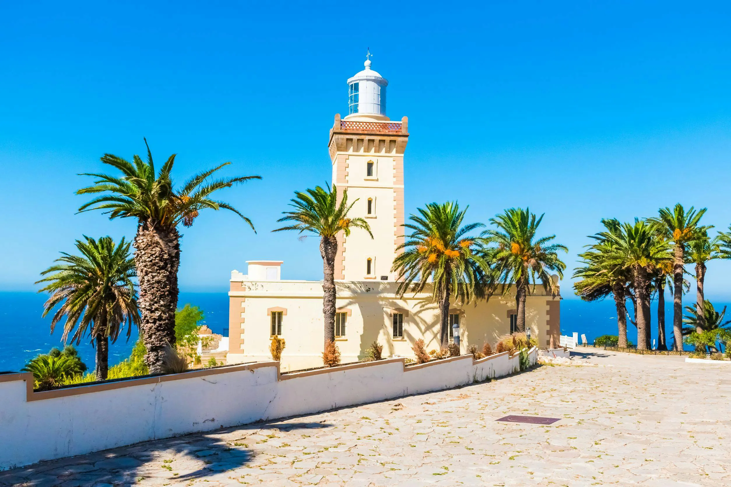 Lighthouse at Cap Spartel surrounded by palm trees, overlooking the ocean in Tangier.