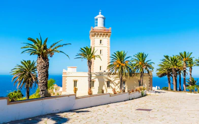 Lighthouse at Cap Spartel surrounded by palm trees, overlooking the ocean in Tangier.