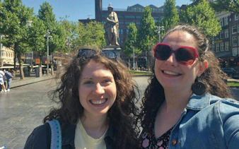 Two people smiling in front of Rembrandt statue in Amsterdam during a city exploration game.