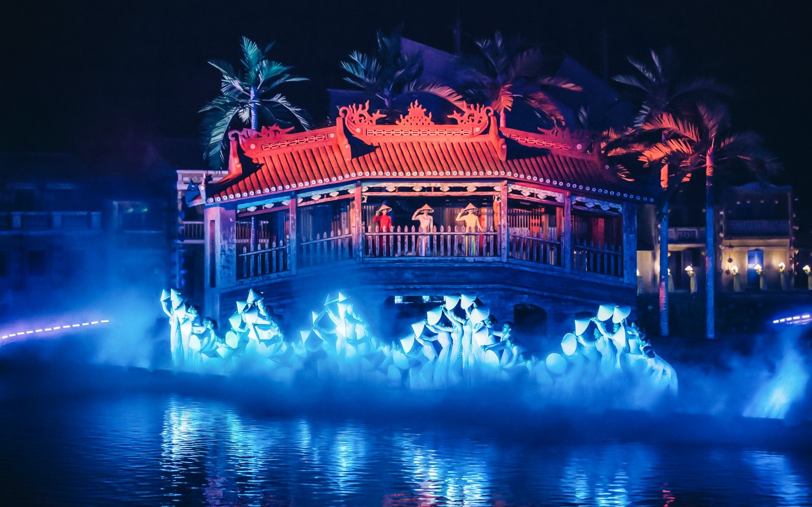 Hoi An Memories Show with performers on a lit stage over water, featuring traditional architecture.