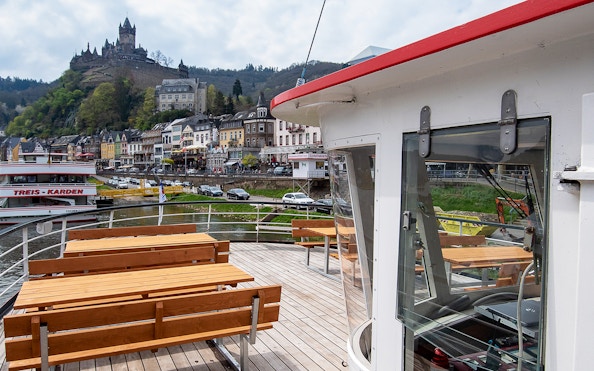 Cruise ship deck with view of Cochem Castle and riverside town in Germany.